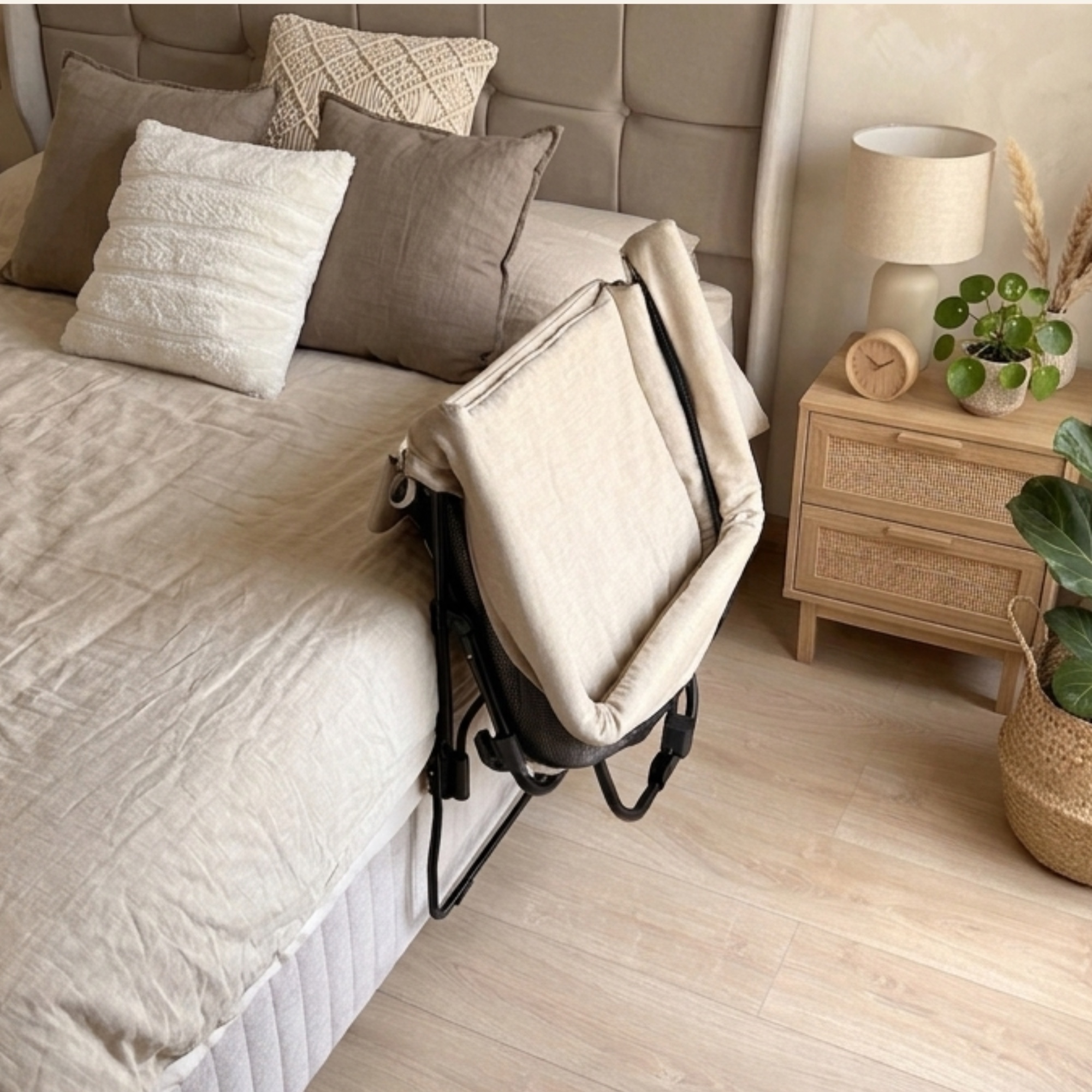 The co-sleeper folded flat and resting against the side of a bed